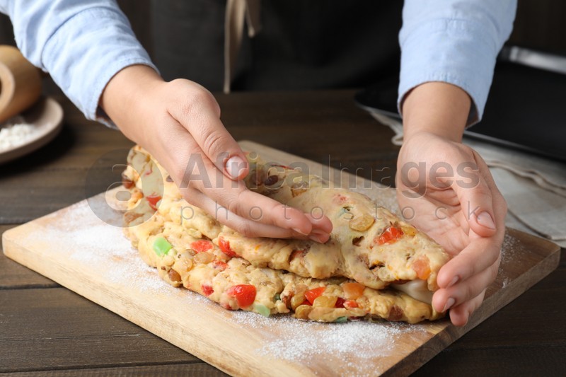 Woman making Stollen with candied fruits and raisins on wooden board at table, closeup