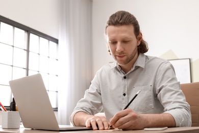 Young man working with laptop at desk in home office