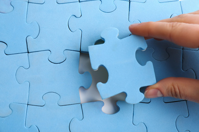 Photo of Woman putting light blue puzzle together, closeup. Career promotion concept