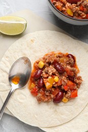 Tasty chili con carne with tortillas on light table, flat lay