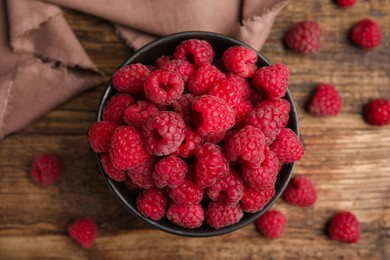 Bowl with fresh ripe raspberries on wooden table, flat lay