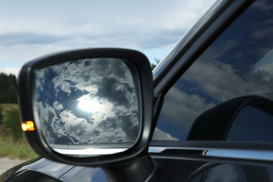 Photo of New black modern car outdoors, closeup of side rear view mirror