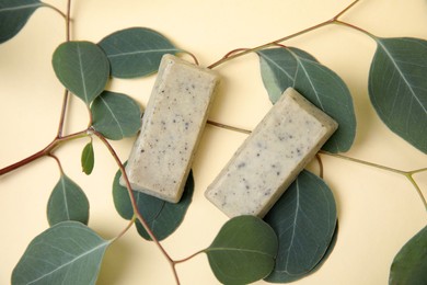 Soap bars and green leaves on beige background, flat lay. Eco friendly personal care product