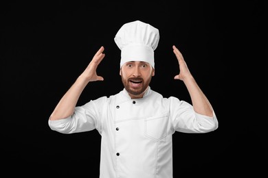 Photo of Emotional mature male chef on black background