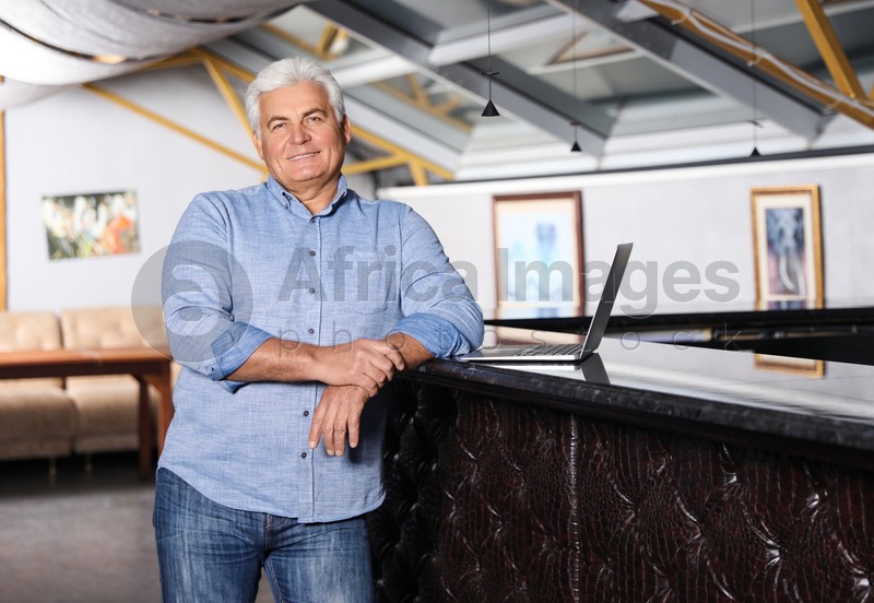 Senior business owner with laptop in his restaurant