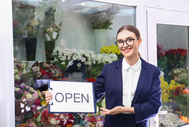 Photo of Female business owner holding OPEN sign near flower shop