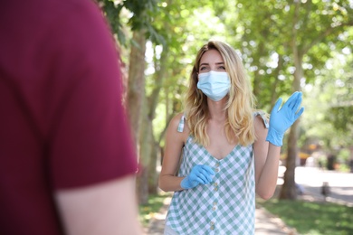 Woman in protective face mask saying hello outdoors. Keeping social distance during coronavirus pandemic