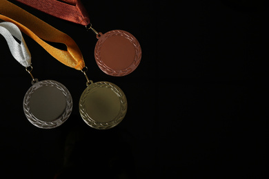 Gold, silver and bronze medals on black background, flat lay. Space for design