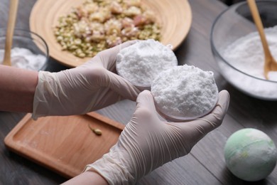 Woman in gloves making bath bomb at table, closeup