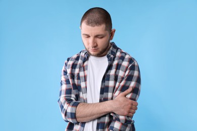 Upset man in shirt on light blue background