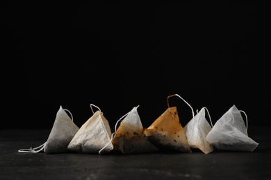 Pyramid tea bags on dark table against black background. Space for text