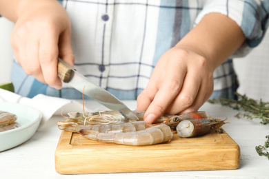 Woman cutting fresh shrimp at table, closeup
