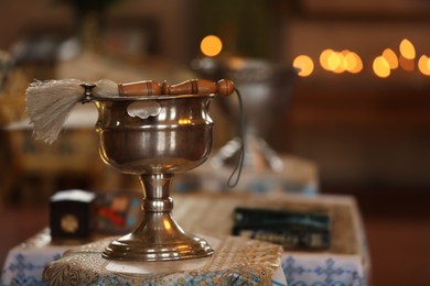Silver vessel with holy water and brush on stand in church, space for text. Baptism ceremony