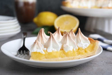 Piece of delicious lemon meringue pie served on grey table, closeup