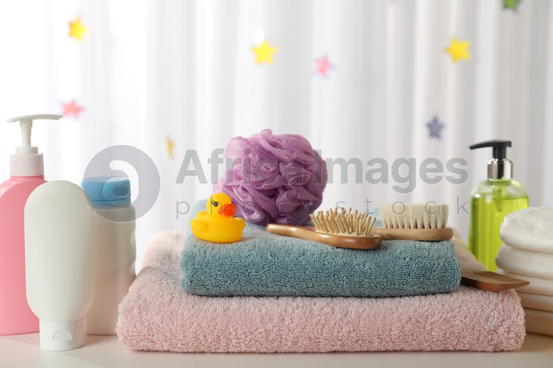 Towels, rubber duck and baby care products on white table indoors