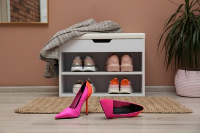 Shelving unit and stylish shoes on floor in hall