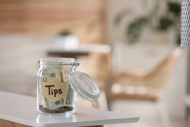 Glass jar with tips on table indoors. Space for text