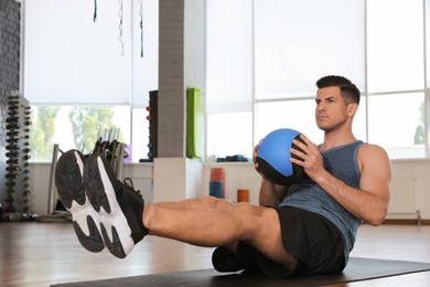 Athletic man exercising with medicine ball in modern gym