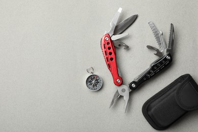 Compact portable multitool, case and compass on light grey background, flat lay. Space for text