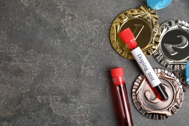Photo of Medals and tubes of blood with words Doping test on grey stone table, flat lay. Space for text