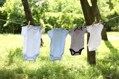 Baby onesies hanging on clothes line outside