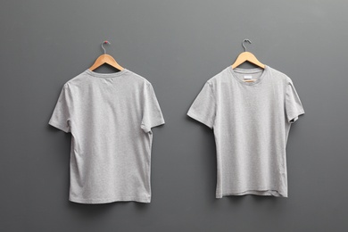 Hangers with blank t-shirts on grey background. Mockup for design