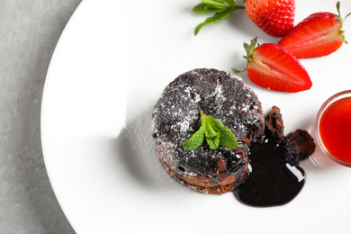 Delicious warm chocolate lava cake with mint and strawberries on plate, above view
