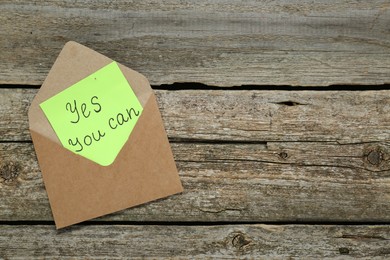 Photo of Envelope and phrase Yes You Can on wooden table, top view with space for text. Motivational quote