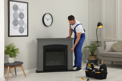 Professional technician installing electric fireplace in room