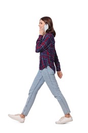 Photo of Happy young woman in casual outfit talking on smartphone while walking against white background