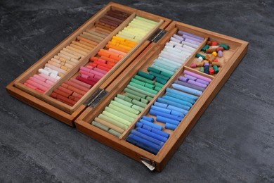 Set of colorful pastels in wooden box on grey stone table. Drawing materials