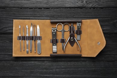 Photo of Manicure set in case on black wooden table, top view