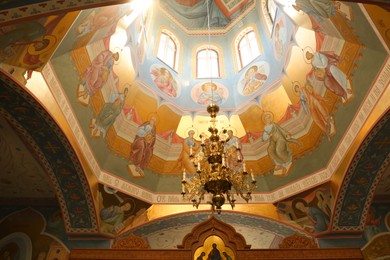 Photo of Beautiful church interior with chandelier and dome vault, low angle view