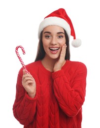 Excited young woman in red sweater and Santa hat holding candy cane on white background. Celebrating Christmas