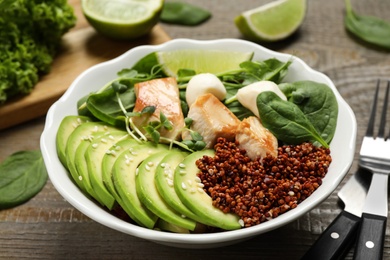 Delicious avocado salad with chicken on wooden table
