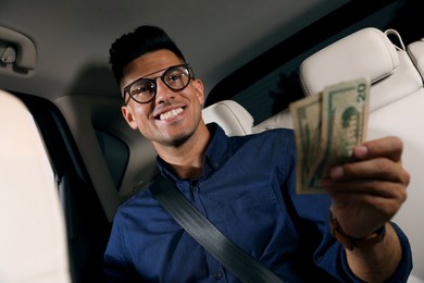 Businessman with money on backseat of modern taxi