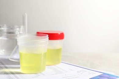 Containers with urine samples for analysis and glassware on test forms against grey background, space for text