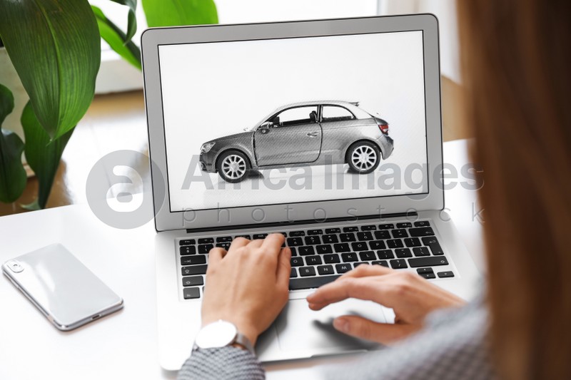 Woman using laptop to buy car at table indoors, closeup