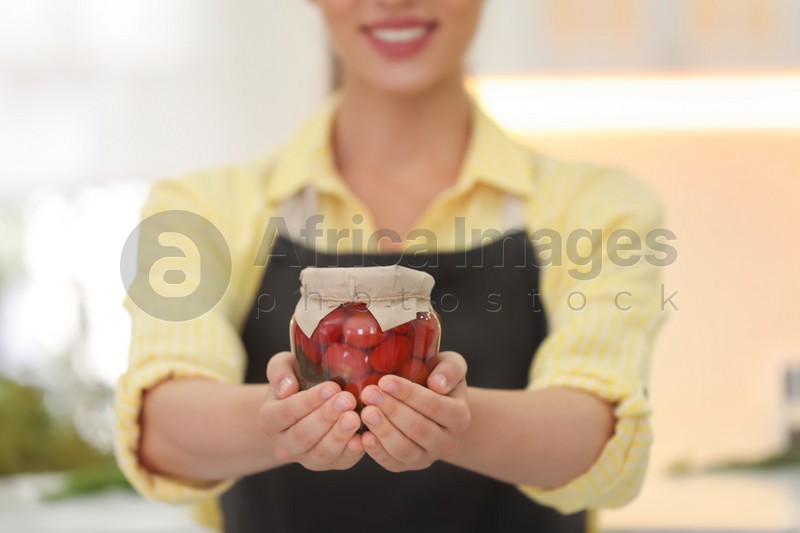 Photo of Woman holding jar of pickled vegetables in kitchen, closeup