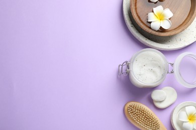 Photo of Flat lay composition with body scrub and plumeria flowers on violet background, space for text