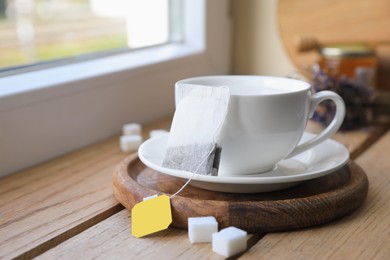 Tea bag and cup on wooden table indoors