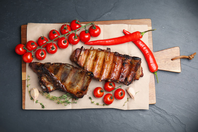 Photo of Tasty grilled ribs on black table, flat lay