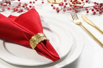Photo of Stylish table setting with red fabric napkin, beautiful decorative ring and festive decor, closeup