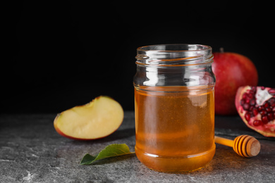 Honey near pomegranate and apple on grey table. Rosh Hashanah holiday