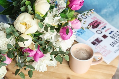 Photo of Bouquet with beautiful flowers and cup of coffee on table