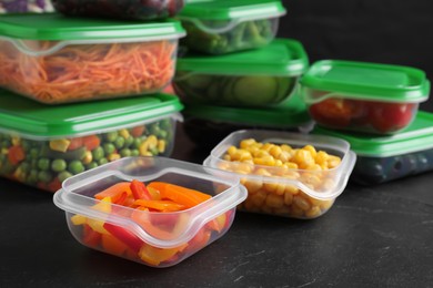 Set of plastic containers with fresh food on black table