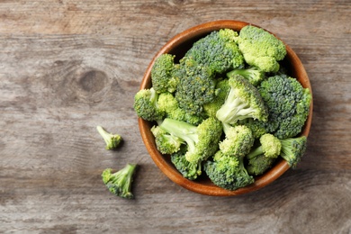 Bowl with fresh green broccoli on wooden background, top view
