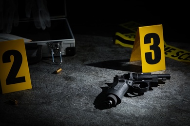Photo of Shell casing, gun and crime scene marker on grey stone table