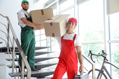 Male movers carrying boxes in new house