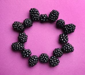 Frame of ripe blackberries on purple background, flat lay. Space for text